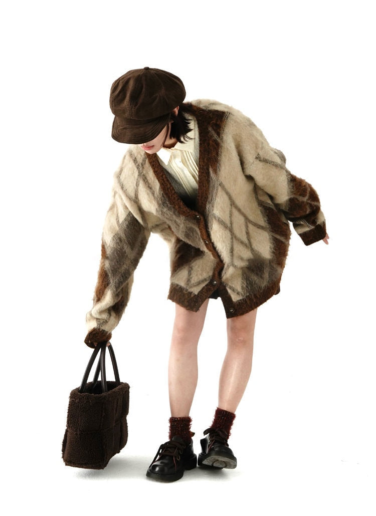 Brown and cream argyle cardigan shown in a leaning pose, with long sleeves and a relaxed silhouette. Cardigan only.